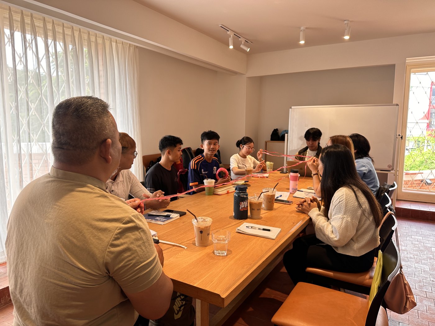 Participants at the Men's Dialogue session pass a length of red string around the table during the opening icebreaker